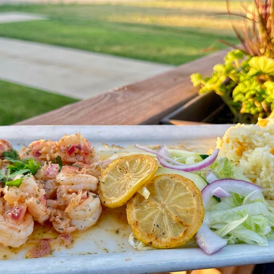 Grilled shrimp with roasted lemon slices, corn rice, and fresh lettuce-onion salad on a blue plate outdoors.